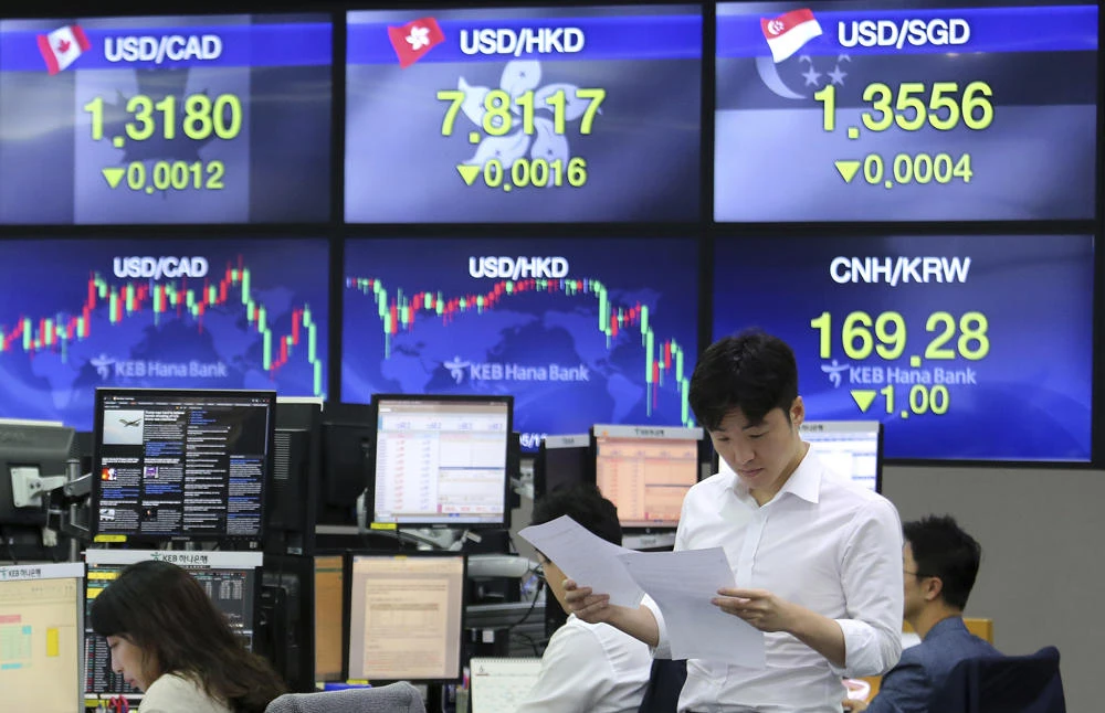 A currency trader reads documents at the foreign exchange dealing room of the KEB Hana Bank headquarters in Seoul, South Korea, on June 21, 2019. Economists warn that a damaging global currency war pitting everyone against everyone could erupt as a result of US President Trump's campaign against "unfair" exchange rates. (AP Photo)