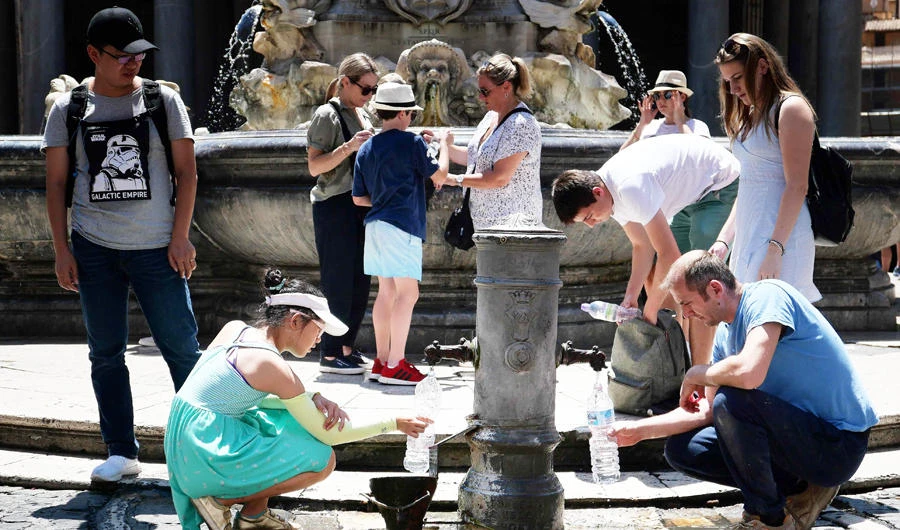 Tourists drink and fill their bottle from a public fountain to refresh themselves during an unusually early summer heatwave on June 24, 2019 in Rome. (AFP)