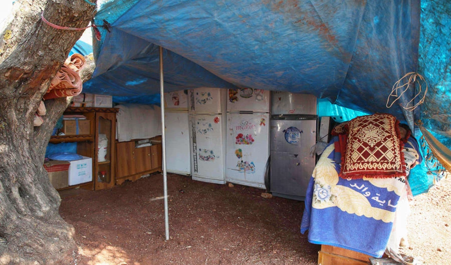 Fridges and other appliances of displaced Syrian families are stored in a tent to protect them from the elements in a field near a camp for displaced people at the village of Atme, in the northern Idlib province on June 13, 2019. (AFP)