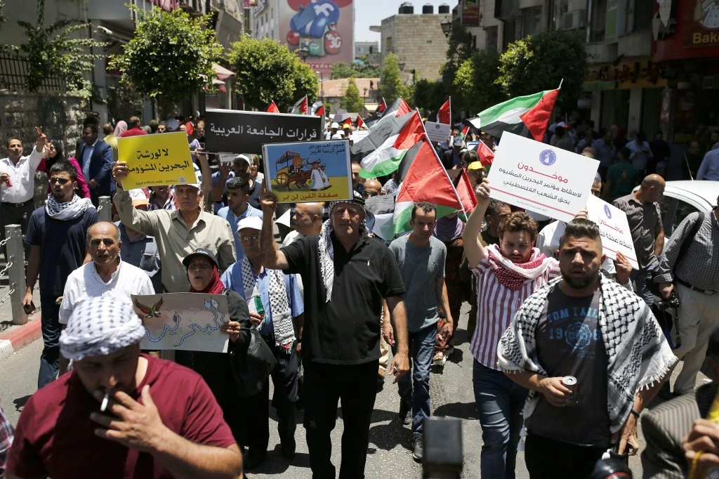 Palestinian demonstrators carry banners during a protest against the US-led Peace to Prosperity conference in Bahrain, in the West Bank city of Ramallah on Monday, June 24, 2019.