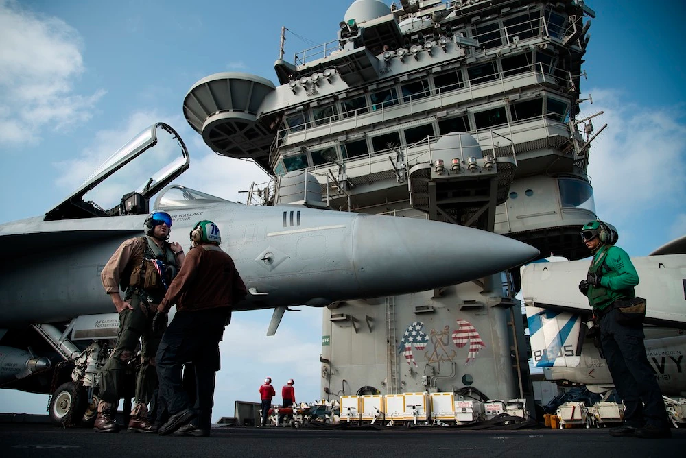 A pilot speaks to a crew member by an F/A-18 fighter jet on the deck of the USS Abraham Lincoln aircraft carrier in the Arabian Sea. (AP/File)