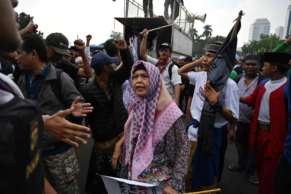 A woman argues with plain-clothed police during a protest near the constitutional court in Jakarta on June 26, 2019, a day before the court reads their decision on defeated presidential challenger's claim that Indonesia's 2019 election was rigged, allegations that spawned deadly rioting in May. (AFP / BAY ISMOYO)