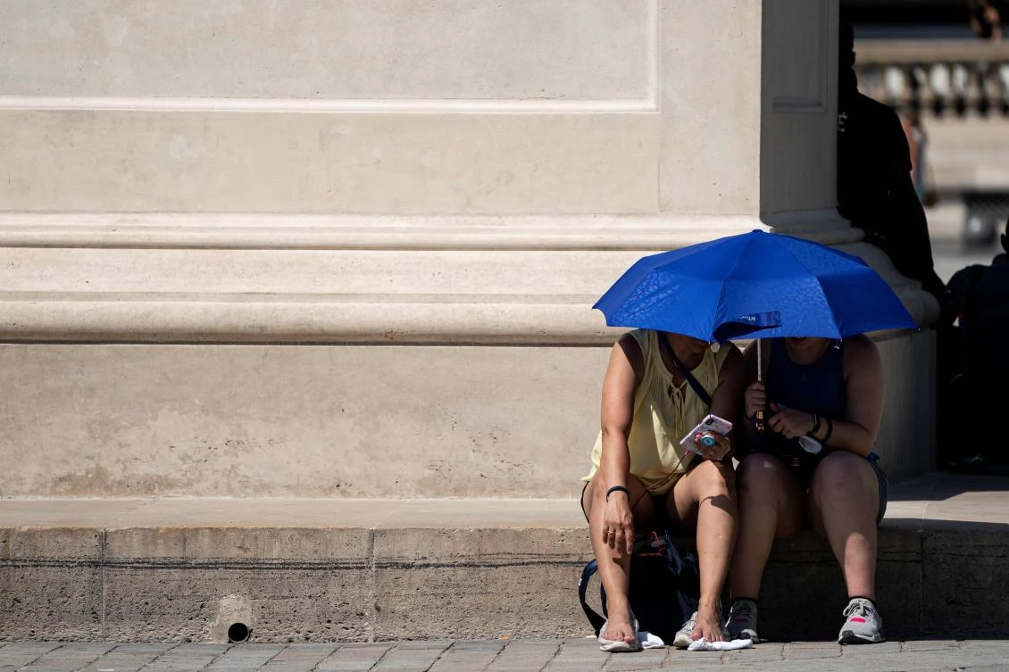 People use an umbrella to shelter from the sun during a heatwave in Paris. (AFP)
