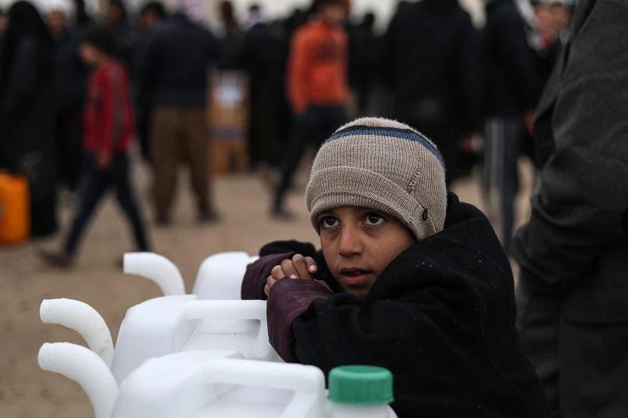 A Syrian boy leans on new jerry cans as he watches aid items to cope with the winter weather being delivered to the Al-Hol refugee camp in Al-Hasakah governorate in northeastern Syria on January 07, 2019. (File/AFP/Delil Souleiman)