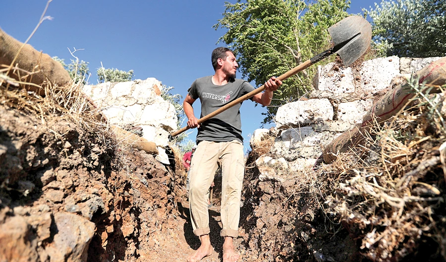 A volunteer uses a shovel to dig a trench in the town of Salqin, Syria. (Reuters)