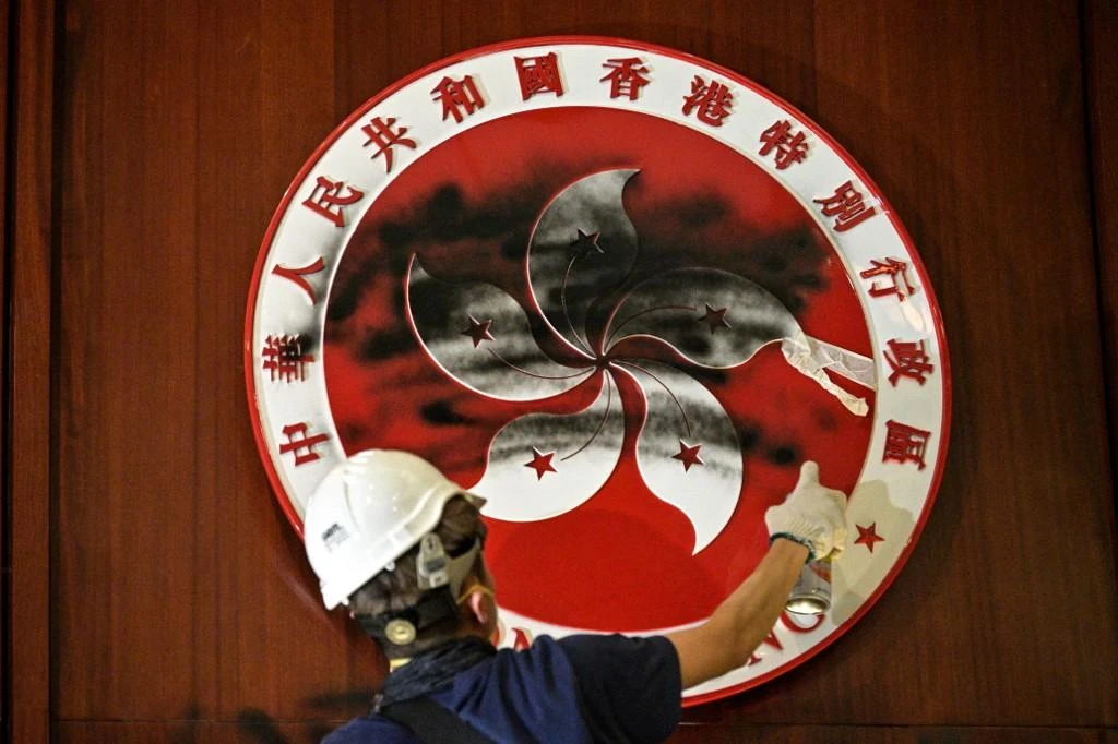 A protester defaces the Hong Kong emblem after breaking into the government headquarters on July 1, 2019, the 22nd anniversary of the city’s handover from Britain to China. (AFP)