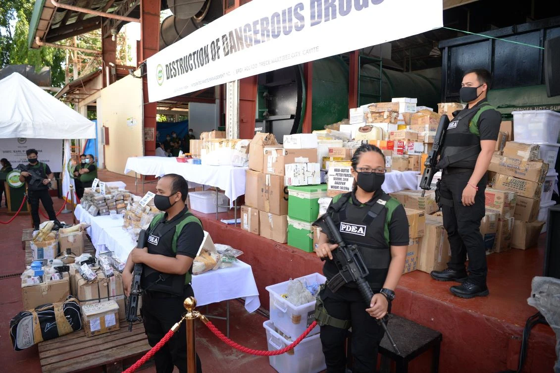 Armed agents of the Philippine Drug Enforcement Agency stand guard next to seized illegal drugs including bricks of cocaine prior to destroying them on July 4, 2019. (AFP)