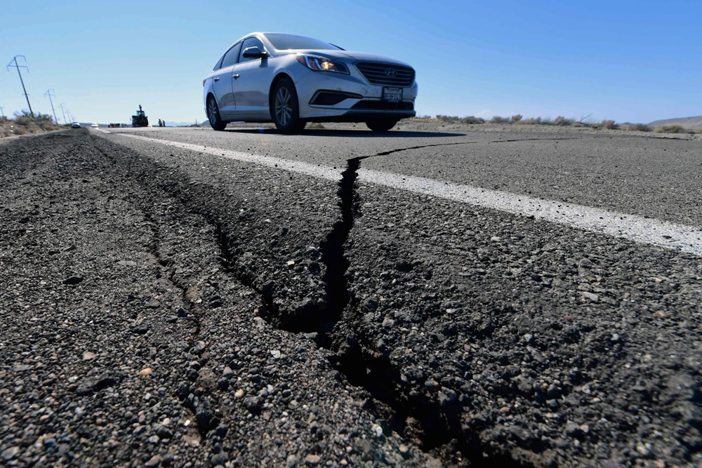 A car drives past a crack in the road after a 6.4-magnitude earthquake in Ridgecrest, California, on July 4, 2019. S(AFP / FREDERIC J. BROWN)