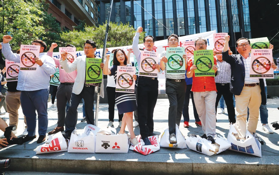 South Korean merchants protest outside the Japanese embassy in Seoul on Friday, trampling boxes symbolizing Japanese products during a rally to denounce Japan curbing the export of high-tech materials to South Korea. (AP)