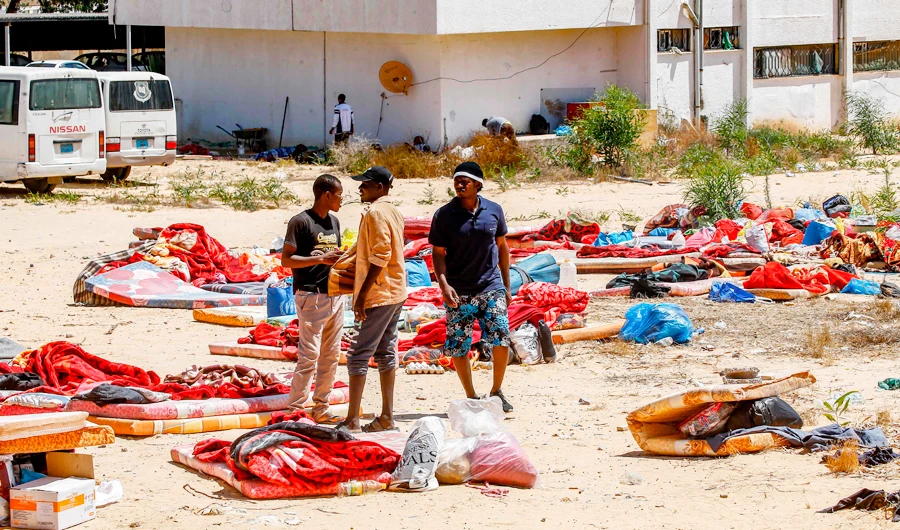 Migrants stand and walk outside at a detention centre used by the Libyan Government of National Accord (GNA) in the capital Tripoli's southern suburb of Tajoura on July 3, 2019, following an air strike on a nearby building that left dozens killed the previous night. (AFP)