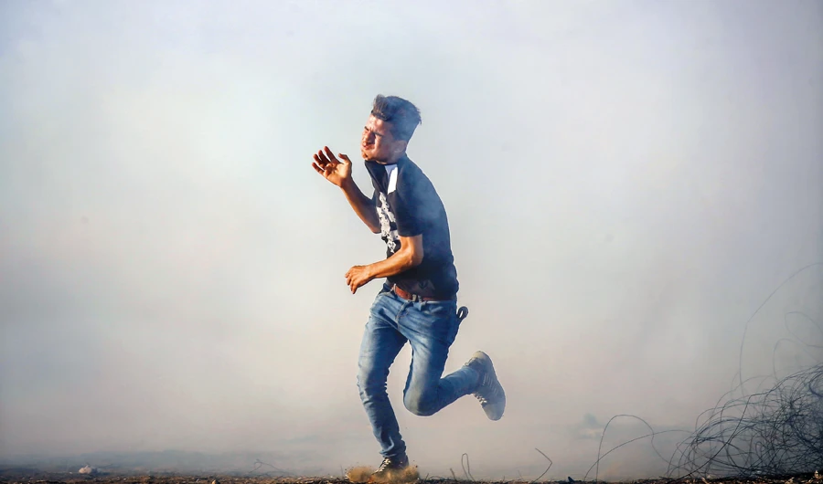 A Palestinian protester flees from tear gas fired by Israeli forces during protests along the Gaza border. (AFP/File)