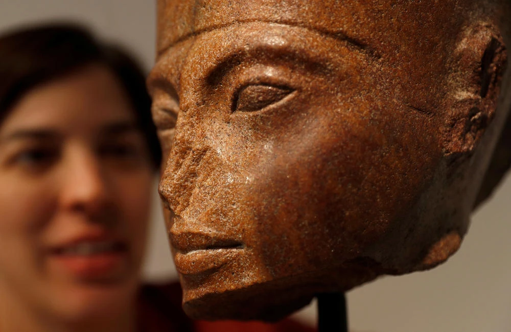 Laetitia Delaloye, head of antiquities of Christie's, poses for a photograph with an Egyptian brown quartzite head of the God Amen prior to its' sale at Christie's auction house in London on July 4, 2019. (REUTERS/Peter Nicholls)