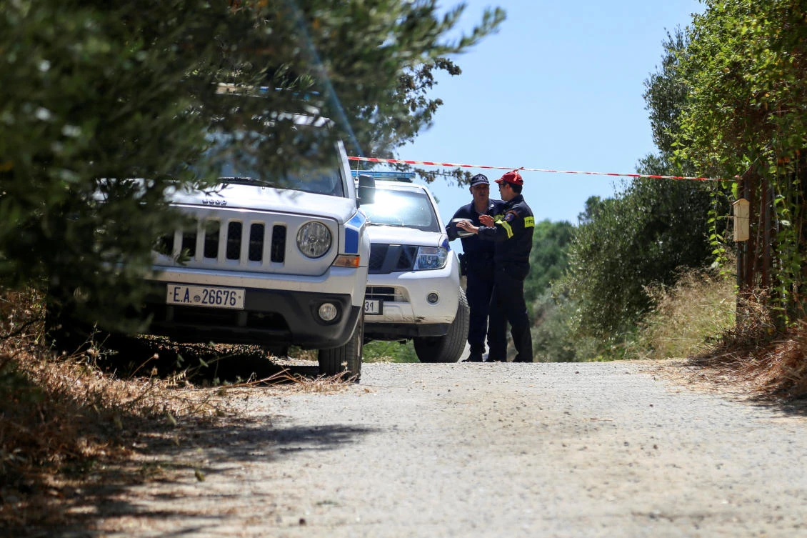 A police officer and a member of a fire brigade search and rescue team stand behind a police cordon, in an area where the body of a woman was found, near the village of Kolimpari on the island of Crete. (Reuters)