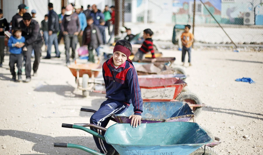 Syrian children wait to carry customers' goods using wheelbarrows, in front of the Tazweed Center at the Al-Zaatari refugee camp in the Jordanian city of Mafraq, near the border with Syria, December 7, 2014. (Reuters)