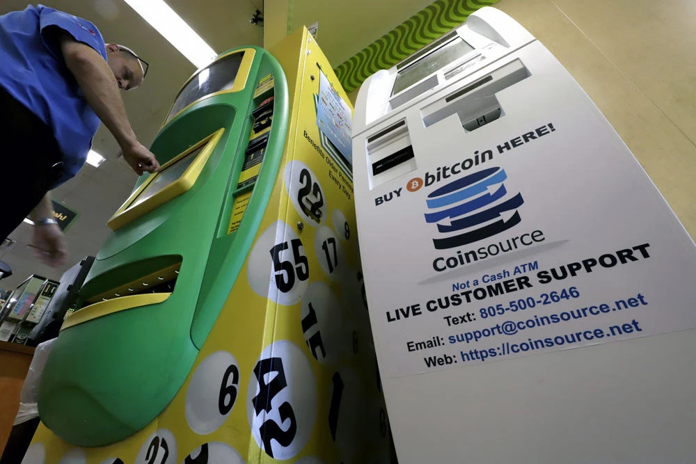 A man makes a purchase from a Pennsylvania Lottery machine, left, next to a Bitcoin ATM machine in a Sheetz convenience store in Pittsburgh, on July 9, 2019. Sheetz, a Pennsylvania-based convenience store chain, is putting Bitcoin ATMs in six shops around the state and one in North Carolina, giving customers the ability to buy and sell the cryptocurrency with US dollars. (AP Photo/Gene J. Puskar)
