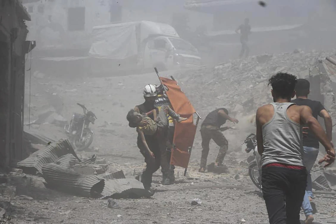 Syrian Civil Defense group known as the White Helmets, shows Civil Defense workers carrying an injured boy in a street that was hit by Syrian government airstrikes, in Jisr Al-Shughur, southwest of Idlib, Syria, Thursday, July 11, 2019. (Syrian Civil Defense White Helmets/AP)
