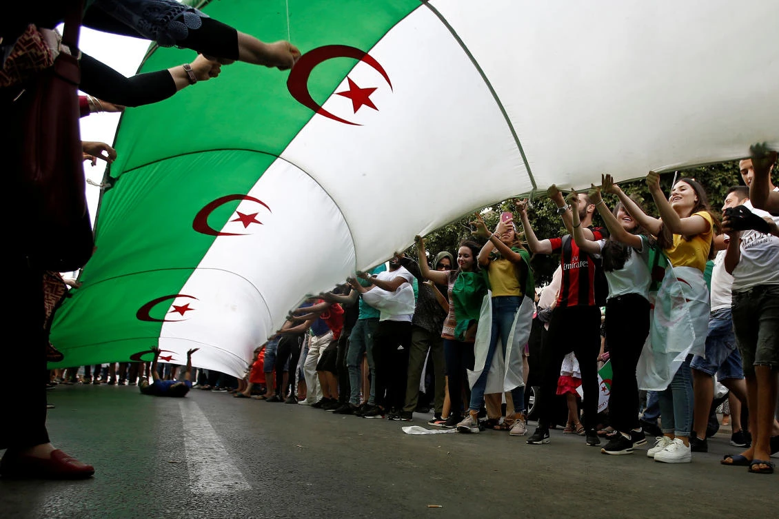Demonstrators hold a national flag during a protest demanding the removal of the ruling elite in Algiers, Algeria July 12, 2019. (Reuters)