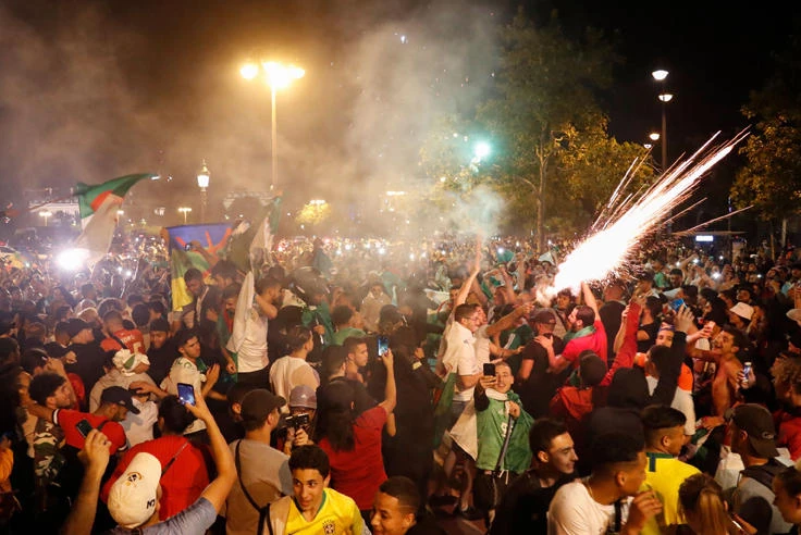 Algeria supporters celebrate on the Champs-Elysee avenue in Paris on July 14, 2019 after Algeria defeated Nigeria in the 2019 Africa Cup of Nations semi-final football match in Cairo. (AFP / Zakaria Abdelkaf)
