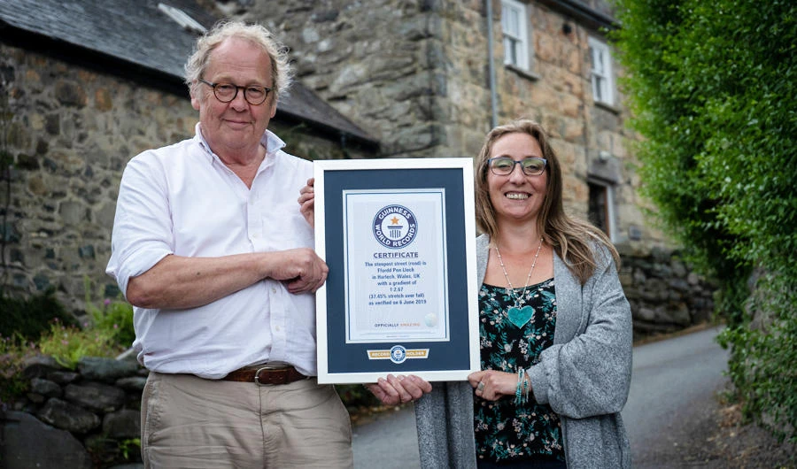Gwyn Headley and Sarah Badham hold a certificate for the record title for world's steepest street, in Harlech, Wales, Britain July 10, 2019, in this handout photo released on July 16, 2019. (Reuters)