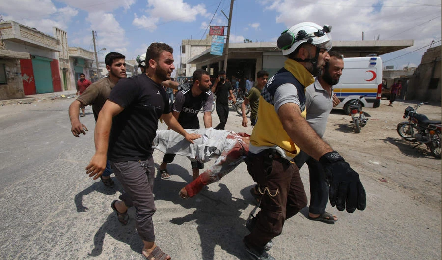 Civilians and a member of the Syrian Civil Defence, also known as the "White Helmets", carry a wounded person following an airstrike by Syrian regime forces in Maaret al-Numan in northwest Syria on July 16, 2019. (AFP / Abdulaziz Ketaz)