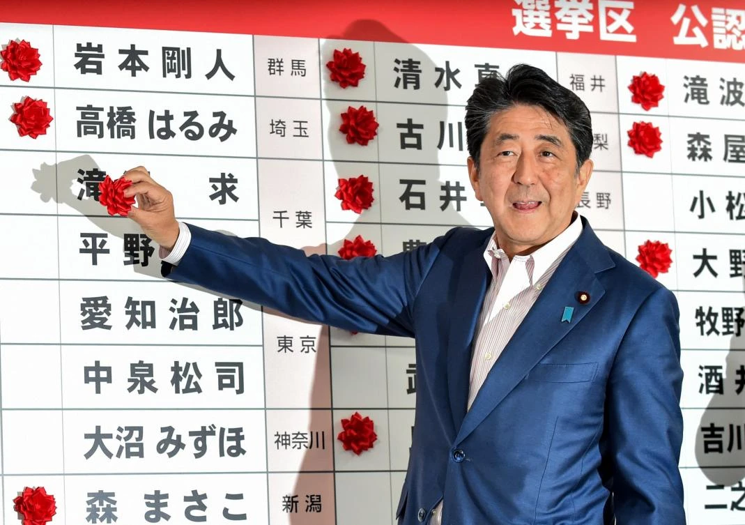 Japanese Prime Minister and ruling Liberal Democratic Party (LDP) president Shinzo Abe attaches paper rosettes on the winning candidates of the Parliament's upper house election at the party's headquarters in Tokyo on July 21, 2019. (AFP)