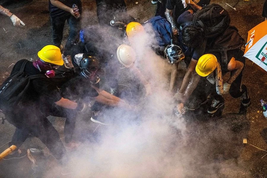 Protesters pour liquid onto a tear gas canister after police fired tear gas to disperse the protesters following a march against a controversial extradition bill in Hong Kong on July 21, 2019. (AFP)