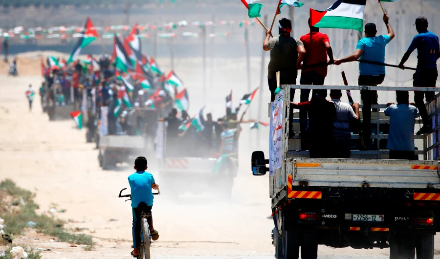 Palestinian demonstrators wave their national flag as they drive toward the border fence with Israel, east of Gaza City on Monday. (AFP)