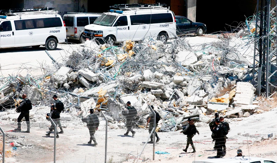This picture taken on July 22, 2019 from the West Bank village of Dar Salah shows Israeli security forces walking past the rubble of a house that underwent a demolition in the area of Sur Baher in East Jerusalem. (AFP)
