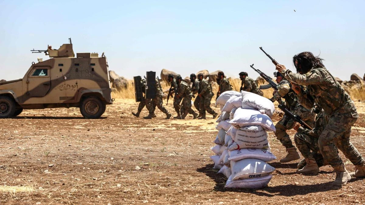 Turkish-backed Syrian fighters run after firing from behind sandbags during a military exercise near Al-Rai in the north of Aleppo province along the border with Turkey on Wednesday, July 24, 2019. (AFP)