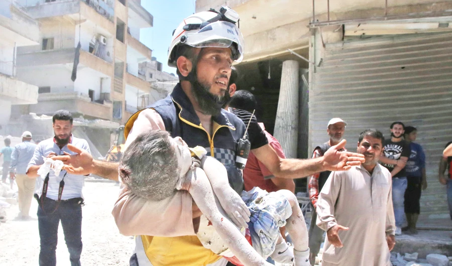 A Syrian Civil Defense rescuer carries a child at the site of an airstrike on the town of Ariha, in the south of Syria's Idlib province, on Saturday. (AFP)