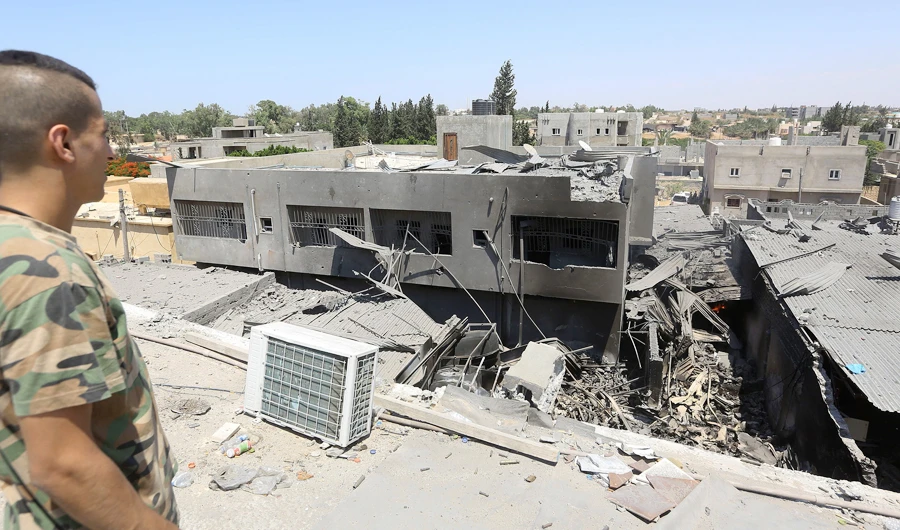 A fighter loyal to the Libyan Government of National Accord (GNA) forces checks the ruins of a building near the the Yarmouk military compound, following airstrikes south of the Libyan capital Tripoli. (AFP)