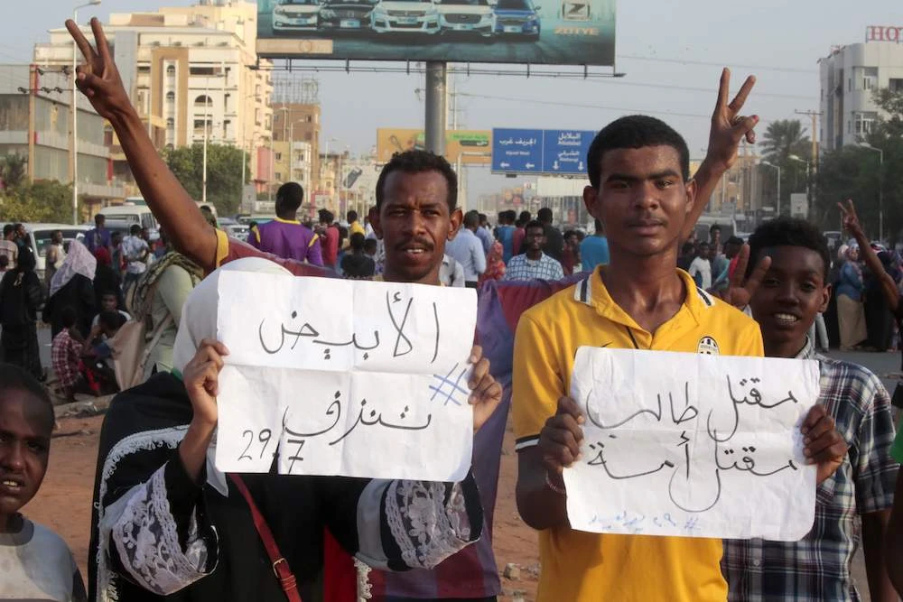 Sudanese protesters carry placards during a rally in the capital Khartoum to condemn the “massacre” of five demonstrators including four high school students at a rally in a central town of Al-Obeida on July 29, 2019. The placards read in Arabic : (R) ” the killing of a student is the killing of a nation” (L) ” AL-Obeida is bleeding.” (AFP)