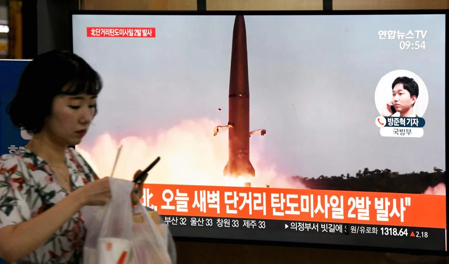 A woman walks past a television news screen showing file footage of a North Korean missile launch, at a railway station in Seoul on July 31, 2019. (AFP)