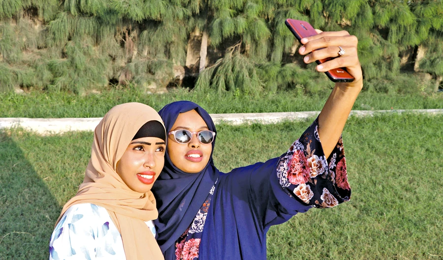 Rahma Abdullahi Mohamud, right, and Hani Hussein take selfies pictures, after buying clothes designed by fashion designer Muna Mohamed Abdullahi, at Peace Garden in Mogadishu, Somalia. (AFP)