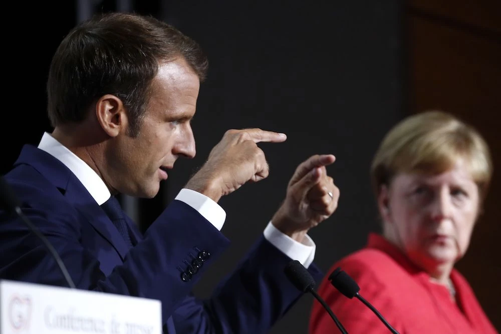 French President Emmanuel Macron (L) gestures as German Chancellor Angela Merkel listens on during a press conference on the situation in Sahel during the G7 summit in Biarritz, south-west France on Aug. 25, 2019, on the second day of the annual summit. (AFP)