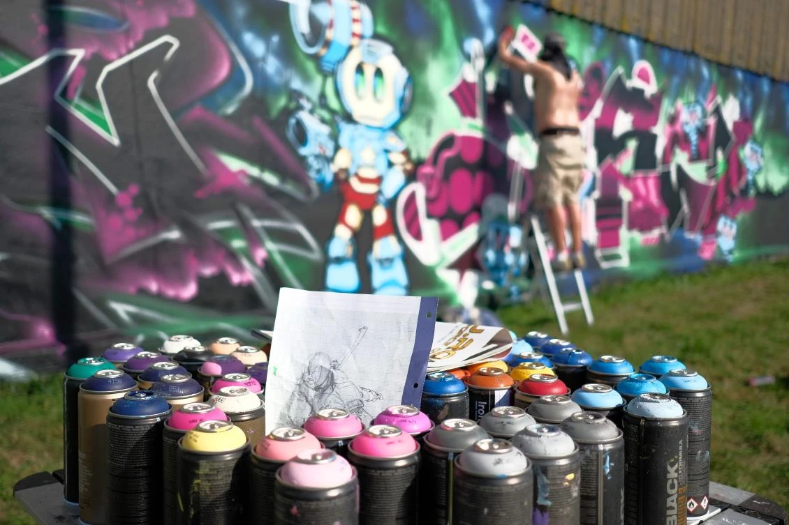 Artists spray Graffiti on a wall in the harbor in Bremerhaven, northern Germany, on August 24, 2019. Every year Graffiti artist can paint a wall on a factory building on a length of 400 meter. / AFP / PATRIK STOLLARZ
