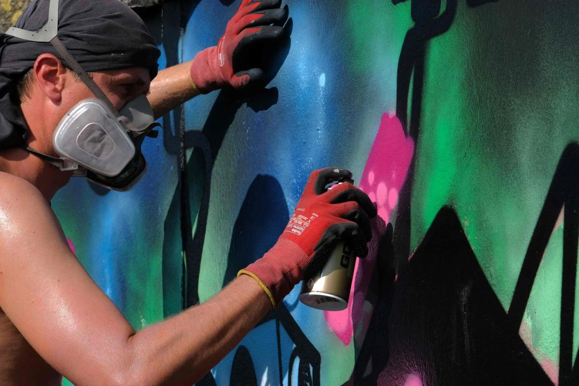 Artists spray Graffiti on a wall in the harbor in Bremerhaven, northern Germany, on August 24, 2019. Every year Graffiti artist can paint a wall on a factory building on a length of 400 meter. / AFP / PATRIK STOLLARZ