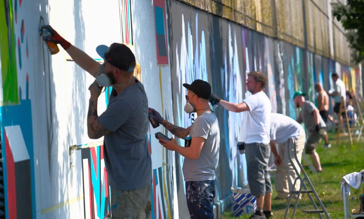 Artists spray Graffiti on a wall in the harbor in Bremerhaven, northern Germany, on August 24, 2019. Every year Graffiti artist can paint a wall on a factory building on a length of 400 meter. / AFP / PATRIK STOLLARZ
