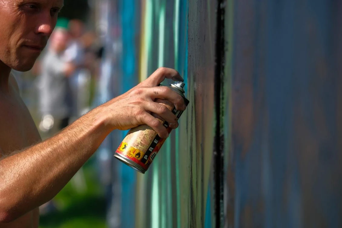 Artists spray Graffiti on a wall in the harbor in Bremerhaven, northern Germany, on August 24, 2019. Every year Graffiti artist can paint a wall on a factory building on a length of 400 meter. / AFP / PATRIK STOLLARZ