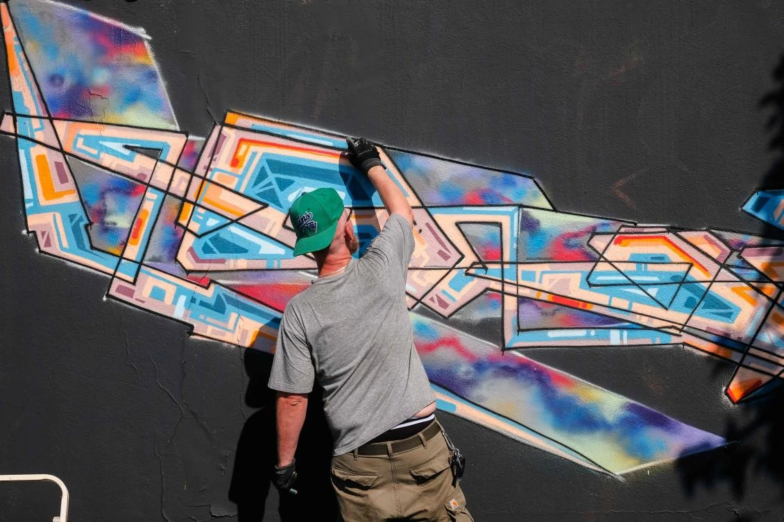 Artists spray Graffiti on a wall in the harbor in Bremerhaven, northern Germany, on August 24, 2019. Every year Graffiti artist can paint a wall on a factory building on a length of 400 meter. / AFP / PATRIK STOLLARZ