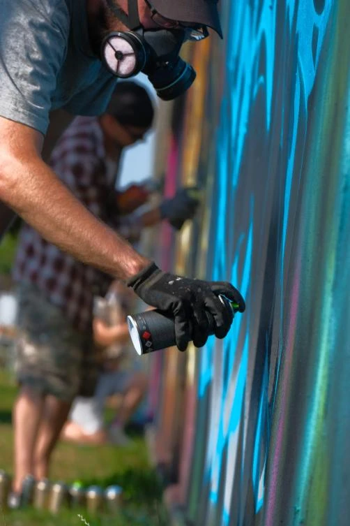 Artists spray Graffiti on a wall in the harbor in Bremerhaven, northern Germany, on August 24, 2019. Every year Graffiti artist can paint a wall on a factory building on a length of 400 meter. / AFP / PATRIK STOLLARZ