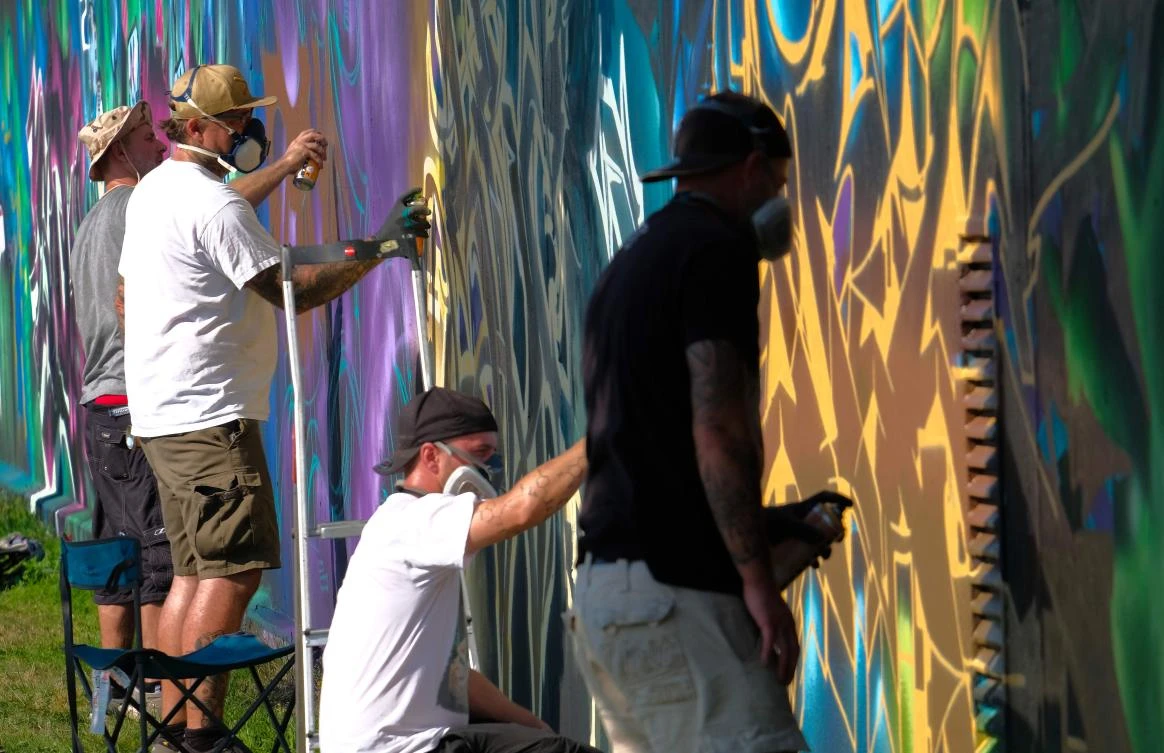 Artists spray Graffiti on a wall in the harbor in Bremerhaven, northern Germany, on August 24, 2019. Every year Graffiti artist can paint a wall on a factory building on a length of 400 meter. / AFP / PATRIK STOLLARZ
