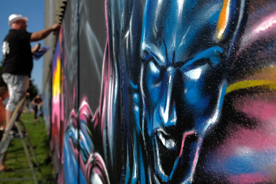 Artists spray Graffiti on a wall in the harbor in Bremerhaven, northern Germany, on August 24, 2019. Every year Graffiti artist can paint a wall on a factory building on a length of 400 meter. / AFP / PATRIK STOLLARZ