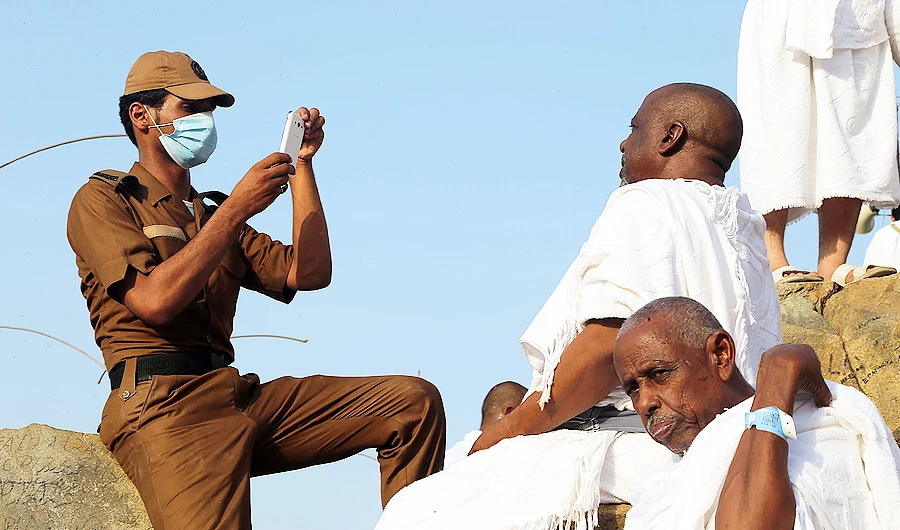 A policeman helps a pilgrim capture a souvenir photo at Arafat. (File/AN photo/Ahmad Hasshad)