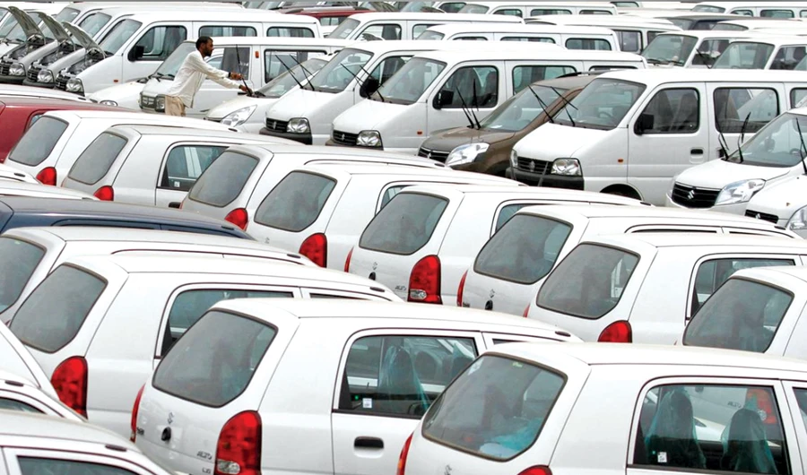A worker adjusts the windscreen wipers of a parked car at a Maruti Suzuki