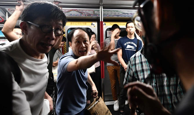 A passenger gestures towards a protester (R) after he prevented the doors of a MTR underground train from closing at Fortress Hill station during morning disruptions to the rush hour commute in Hong Kong on August 5, 2019. (AFP / Anthony Wallace)