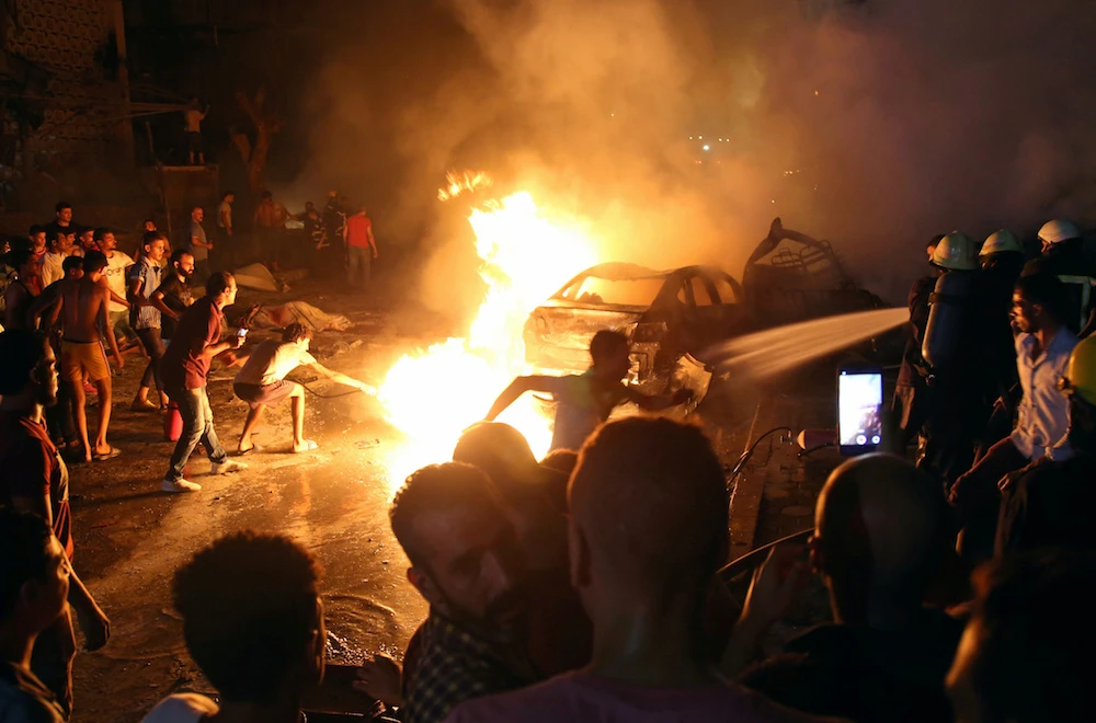 People extinguish a fire from a blast outside the National Cancer Institute, Cairo. (Reuters)