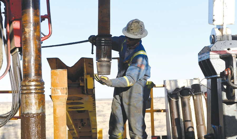 An oil worker removes a thread cap from a piece of drill pipe on a drilling lease owned by Elevation Resources near Midland, Texas. (Reuters)