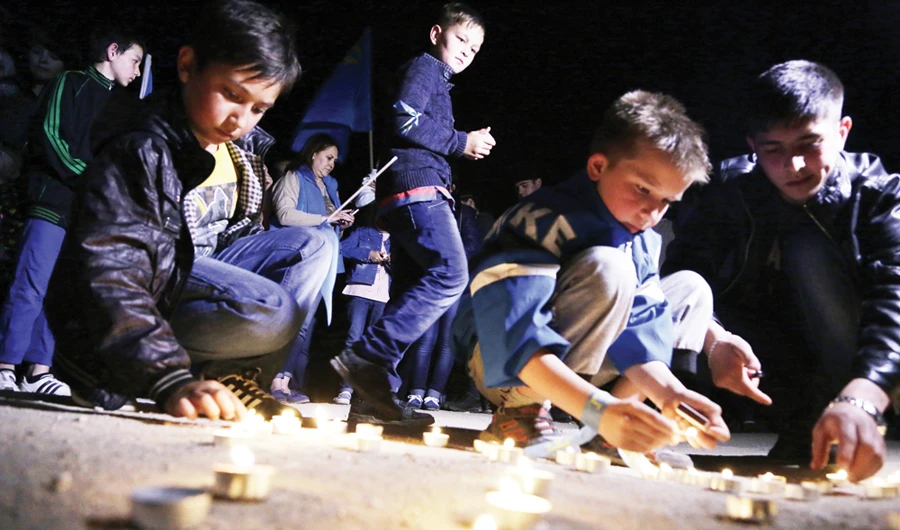 Crimean Tatar boys light candles during a memorial ceremony in 2014 marking the 1944 deportation of Tatars from Crimea — Russia has now banned such gatherings. (AFP)