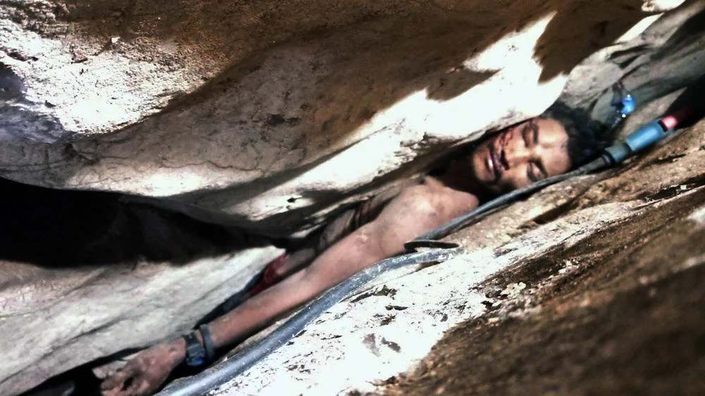 Cambodian Sum Bora gets stuck in a rock's hollow at Battambang province in Cambodia on Aug. 7, 2019 while collecting bat droppings for sale. (Battambang province Authority Police via AP)